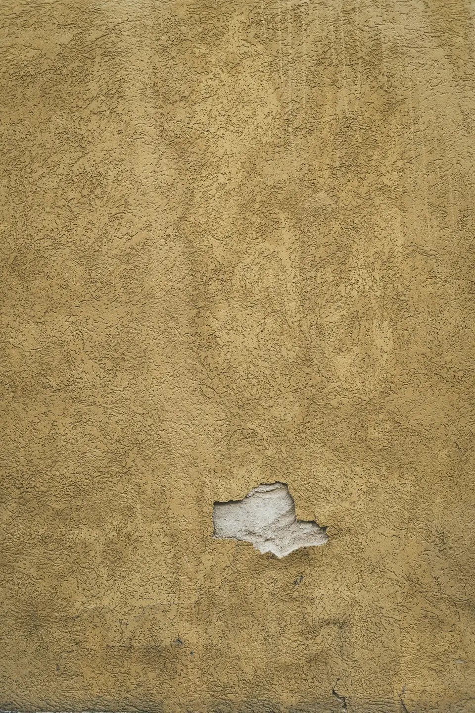 Enduit ocre à la texture irrégulière, légèrement écaillé